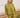 Woman wearing a green knit matching sweater and shorts set standing outdoors with a white wooden structure in the background.