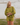 Woman wearing a green knit matching sweater and shorts set standing outdoors with a white wooden structure in the background.