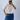 Person wearing a light pink shirt and blue jeans taking a mirror selfie.