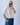 Person wearing a light pink shirt and blue jeans taking a mirror selfie.