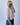 Person taking a mirror selfie wearing a light pink blouse and blue jeans against a white background