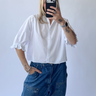 Person wearing a white shirt and blue jeans against a plain background