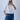 Person wearing a white shirt and blue jeans against a plain background