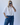 Person wearing a white shirt and blue jeans against a plain background