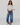 Woman wearing a white blouse and blue jeans against a white background