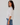 Woman wearing a white shirt and blue jeans against a plain background