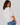 Woman wearing a white blouse and blue jeans against a plain background