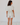Woman wearing a light-colored outfit with ruffled sleeves against a white background