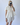 Person wearing a white outfit with ruffled sleeves against a plain background