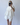 Person wearing a white outfit with ruffled sleeves against a plain background