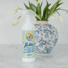 Bottle of Nellie's Wrinkle-B-Gone with Antistatic in front of a vase with white tulips.