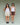 Two women standing next to each other on a green background. One woman is wearing a white tank top with cream shorts, the other woman is wearing a white tank top with brown shorts.