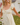 Woman wearing a light yellow dress with puffed sleeves outdoors.