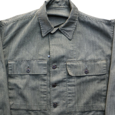 Green denim shirt with button details on a light gray background