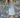 Woman walking on a rocky path wearing a white dress and brown boots.