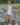 Woman standing on a rocky path wearing a white dress and brown boots.