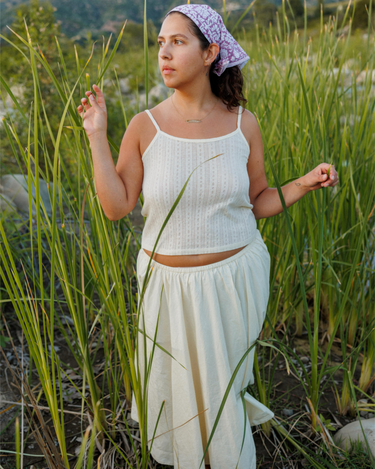 Woman in a white outfit standing in tall grass.