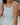 Woman wearing a gold necklace and cream-colored pointelle tank top.