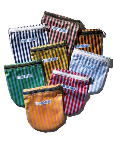Pile of zippered pouches with vertical stripes, featuring a small blue label on the front on a white background.