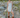 Woman standing on a rocky path wearing a white dress and brown boots.