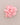 A light pink fabric flower brooch with a gold-tone pin, displayed on a neutral taupe background.