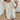 A woman wearing a white, bloomer-style shorts and a matching flowy, feminine top.