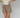 Woman wearing a pair of brown plaid boxer-style shorts with an elastic waistband and ruffle detail at the bottom, paired with a cream shirt.