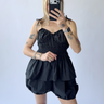 Person wearing a black sleeveless outfit set against a plain background