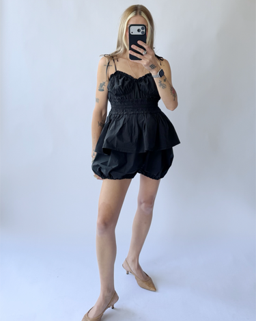 Person wearing a black sleeveless outfit set against a plain background