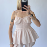 Person wearing a light pink sleeveless outfit set against a plain background