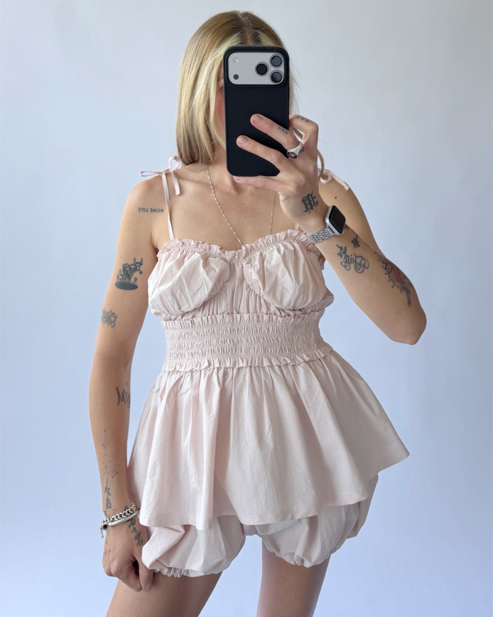 Person wearing a light pink sleeveless outfit set against a plain background