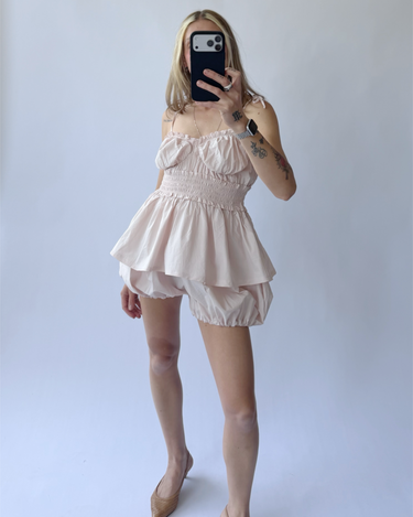 Person wearing a light pink sleeveless outfit set against a plain background