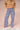 Woman wearing a tan sweater with navy blue and white gingham pants on a beige background.