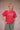 Person wearing a red t-shirt with graphic design on a plain background