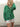 Woman wearing a green cardigan and white shorts against a light background