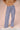 Woman wearing a tan sweater with navy blue and white gingham pants on a beige background.
