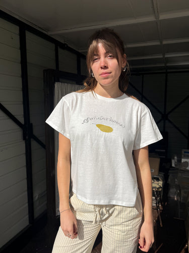 Woman wearing a white t-shirt with a pear graphic and pinstripe pants.