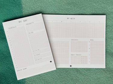 Two planner sheets on a green textured surface, one titled 'My Day' and the other 'My Week'.