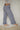 Woman wearing blue plaid casual pants with a ruffled ankle hem against a plain background.