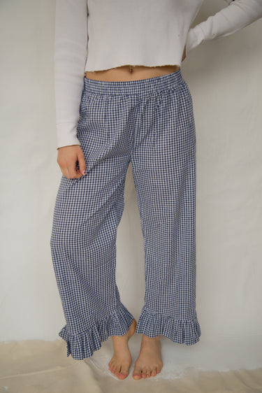 Woman wearing blue plaid casual pants with a ruffled ankle hem against a plain background.