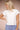 Woman wearing a white t-shirt and blue pants against a beige background
