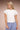 Young person wearing a white t-shirt and blue checkered pants against a beige background