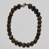 A beaded necklace made of polished brown tiger's eye beads with a small gold clasp, displayed on a plain light gray background.