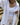 Person wearing a white outfit with a necklace, standing outdoors.