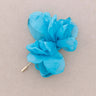 A bright turquoise blue fabric flower brooch with a gold-tone safety pin clasp, displayed on a neutral beige background.