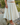 Person wearing a cream skirt standing on rocks with a natural background