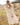 Woman in a cream skirt and sweater standing in a field with mountains in the background