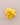 A yellow fabric flower brooch with a gold-tone pin, displayed on a neutral gray background.