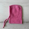 Pink knitted bonnet on a light gray surface