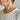 Person wearing a yellow beaded necklace and gold hoop earrings against a plain background